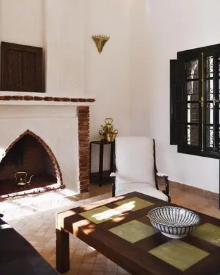 a living room with a fireplace and a table and a chair at Riad Arraha Retreat Elegance tranquility and pools in Marrakech