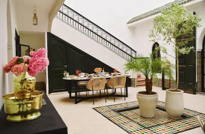 a dining room with a table and chairs and flowers at Riad Arraha Retreat Elegance tranquility and pools in Marrakech