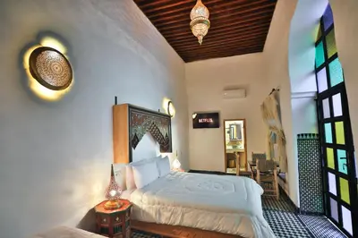 a bedroom with a bed and a table with a lamp at Riad Old City Palace in Fès