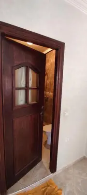 a wooden door in a bathroom with a toilet at Bouznika in Oulad Akkou