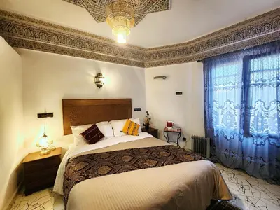a bedroom with a large bed with blue curtains at Riad el Anaqa in Fès