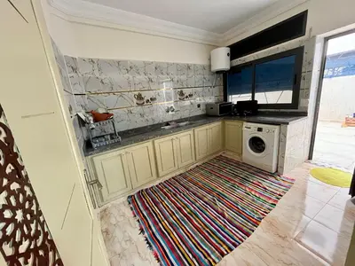 a kitchen with a washing machine and a rug at Saha khedra in Oulad Akkou