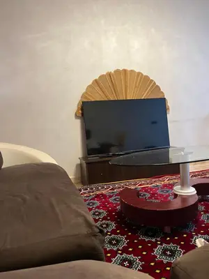a living room with a table and a flat screen tv at Saha khedra in Oulad Akkou