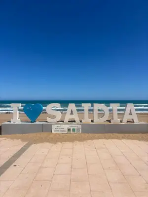 a sign at the beach with the ocean in the background at Saidia Beach appartement in Oulad Akkou