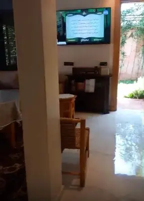 a living room with a tv and a table and a chair at Villa Mina in Aghmat