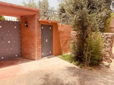 a house with two garage doors and a brick wall at Villa Mina in Aghmat