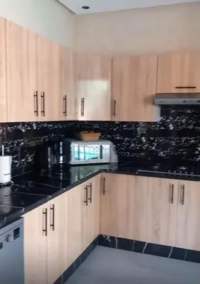 a kitchen with wooden cabinets and black counter tops at Villa Mina in Aghmat