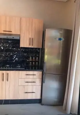 a kitchen with a stainless steel refrigerator and wooden cabinets at Villa Mina in Aghmat