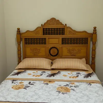 a bed with a wooden headboard with flowers on it at Residence Kawtar Meknès Marjane 2 in Meknès
