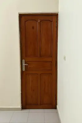 a wooden door in a room with a white wall at Residence Kawtar Meknès Marjane 2 in Meknès