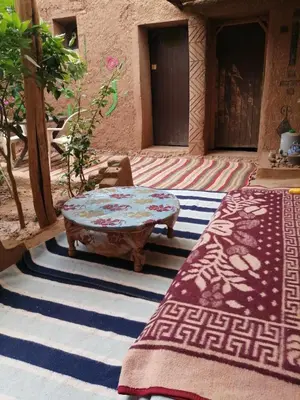 a patio with a table and a rug in front of a building at Dar itran 2 in Mhamid