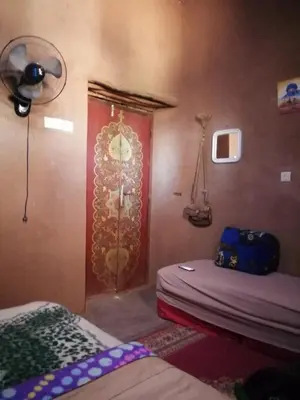 a room with two beds and a door with a clock at Dar itran 2 in Mhamid