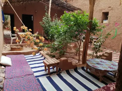 a patio with a table and benches and trees at Dar itran 2 in Mhamid