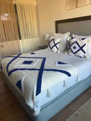 a bed with blue and white sheets and pillows at La Joie de Vivre in Oulad Akkou