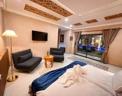 a bedroom with a bed and two chairs and a tv at Atlas Front in Marrakech