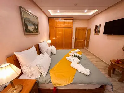 a room with a bed with pillows and a television at Atlas Front in Marrakech