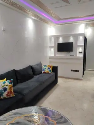 a living room with a couch and a tv on a wall at شقة مفروشة in Oulad Akkou