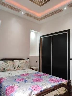 a bedroom with a bed with pink flowers on it at شقة مفروشة in Oulad Akkou
