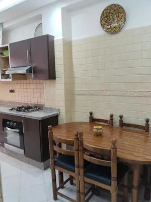 a kitchen with a wooden table and a stove at شقة مفروشة in Oulad Akkou