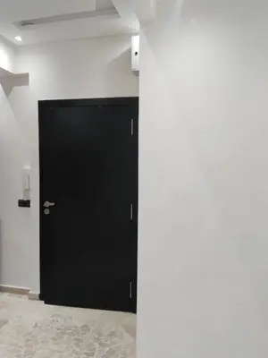 a black door in a room with a white wall at شقة مفروشة in Oulad Akkou