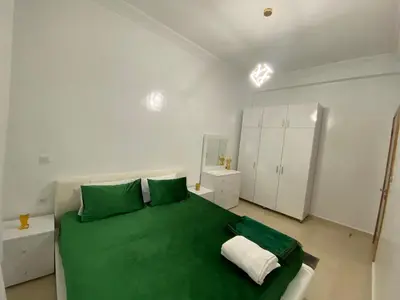 a white bedroom with a green bed and white cabinets at Unique et strategique in Meknès