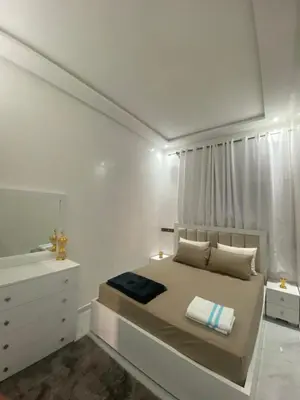 a white bedroom with a bed and a mirror at Unique et strategique in Meknès