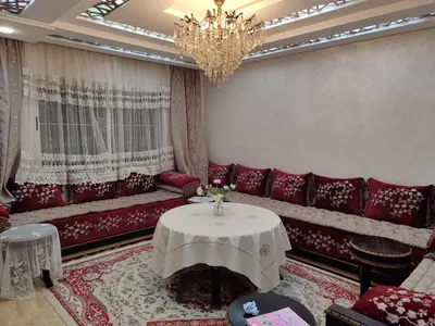 a living room with a red couch and a table at Maison avec piscine in Oulad Akkou