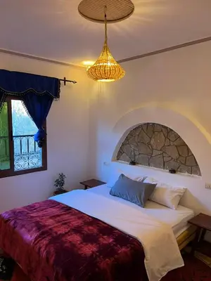 a bedroom with a large bed and a chandelier at Kasbah Ait Marghad in Aït Ougliff