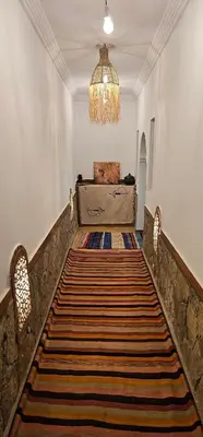 a hallway with a large rug on the floor and a chandelier at Kasbah Ait Marghad in Aït Ougliff