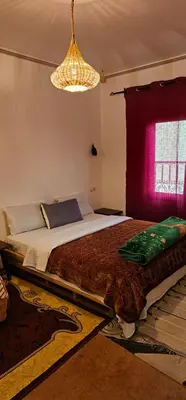 a bedroom with a large bed with a red window at Kasbah Ait Marghad in Aït Ougliff