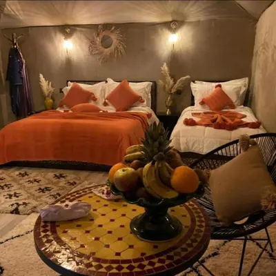 a bedroom with two beds and a table with fruit on it at Traveling Luxury Camp in Merzouga