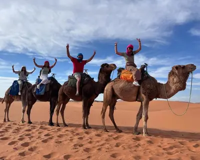 four people riding on camelbacks in the desert at Traveling Luxury Camp in Merzouga