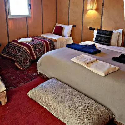 a room with two beds and a chair in it at Traveling Luxury Camp in Merzouga