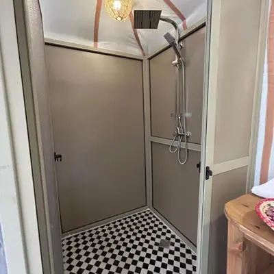 a shower with a glass door with a checkered floor at Traveling Luxury Camp in Merzouga