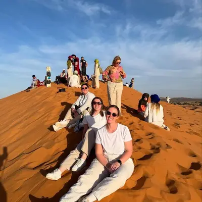 a group of people sitting on a sand dune at Traveling Luxury Camp in Merzouga