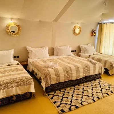 a bedroom with two beds and a mirror on the wall at Traveling Luxury Camp in Merzouga