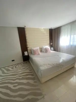 a bedroom with a large white bed with pink pillows at Appartement location hout standing agadir in Oulad Akkou