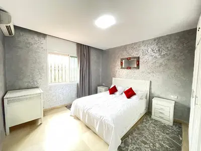 a bedroom with a white bed with red pillows at Atlas appartement in Oulad Akkou