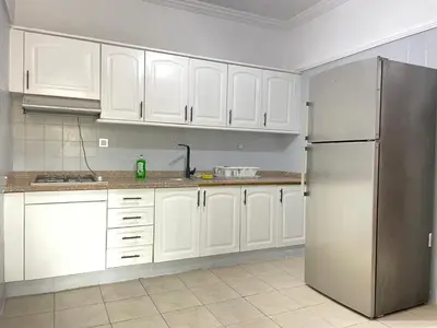 a kitchen with white cabinets and a stainless steel refrigerator at Atlas appartement in Oulad Akkou