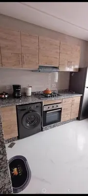 a kitchen with a stove and wooden cabinets at فيلا فاخرة in Imouzzer Kandar