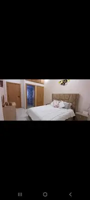 a bedroom with a white bed and a room with a table at فيلا فاخرة in Imouzzer Kandar