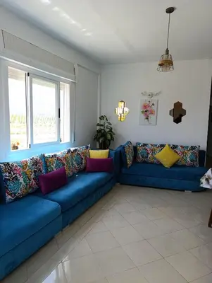 a blue couch with colorful pillows in a living room at Appartement martil in Oulad Akkou