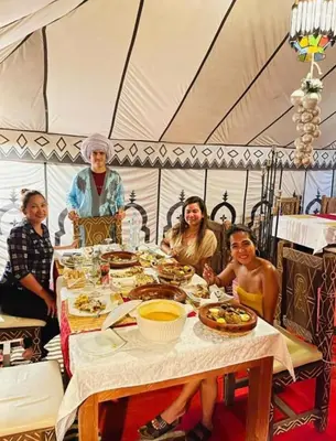 a group of people sitting around a table in a tent at Fantastic Luxury Camp in Merzouga