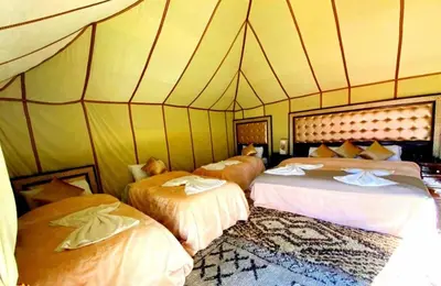 a room with three beds in a tent at Fantastic Luxury Camp in Merzouga