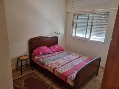 a bedroom with a bed with pink sheets and a window at Al Jazeera beach in Zaouia Sidi Rahkal