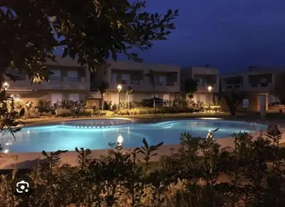 a swimming pool in front of a building at night at Al Jazeera beach in Zaouia Sidi Rahkal