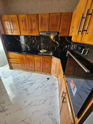 a kitchen with wooden cabinets and marble counter tops at Chaker's Luxury Apartment Fez in Fès