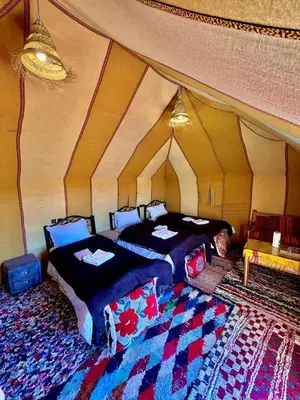 a room with two beds in a tent at Habibi Luxury Camp in Merzouga