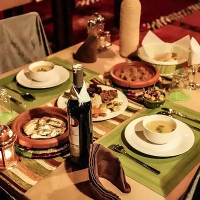 a table with a bottle of wine and plates of food at Habibi Luxury Camp in Merzouga