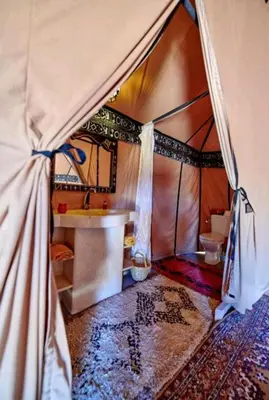 a bathroom with a tent with a sink and a toilet at Habibi Luxury Camp in Merzouga